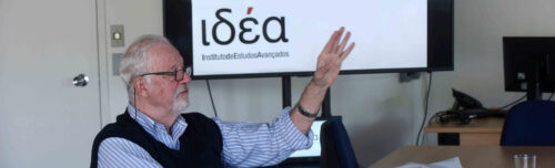 O cineasta e cronista paulistano Ugo Giorgetti em apresentação ao Programa do Artista Residente, no fundo, projeção com o logo do IdEA